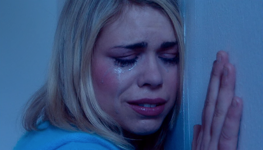 Rose Tyler crying against a wall